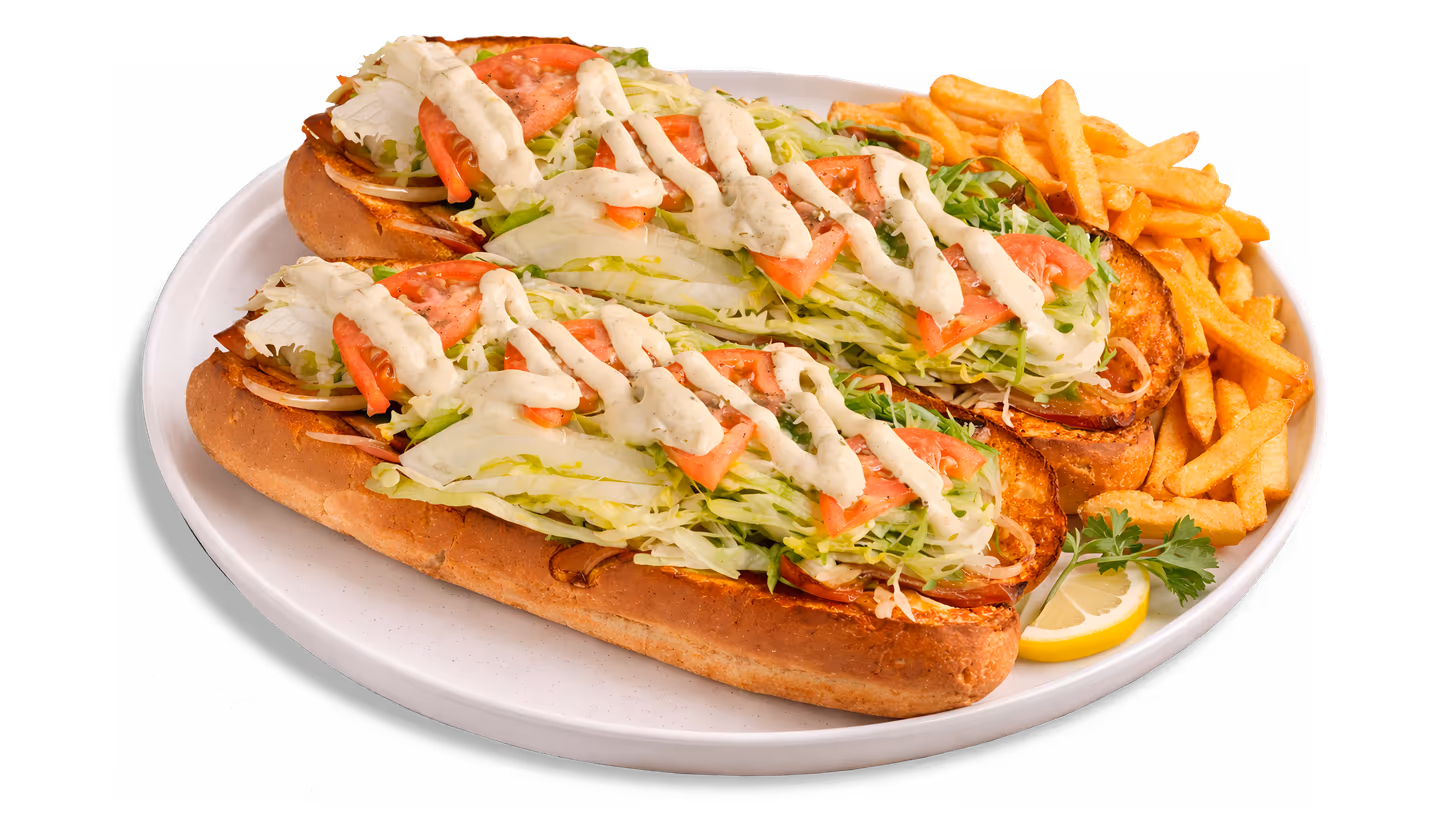 Two lettuce, tomato, onion sandwiches with sauce and a side of French fries on a white plate.
